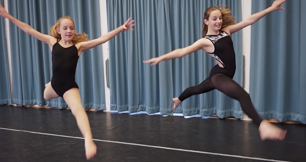 Two students in a dance hall leaping