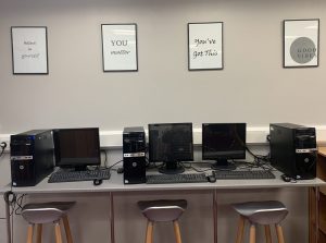 Three computers in the LINC with motivational framed quotes above them