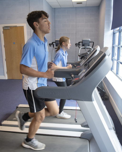 Two students in a gym using the running machine