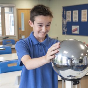 A student touching a large metal ball