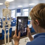 A student taking a photo of a skeleton with a tablet camera.