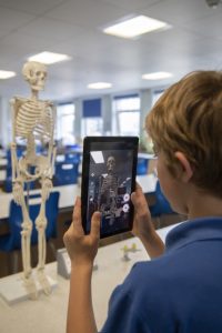 A student taking a photo of a skeleton with a tablet camera.