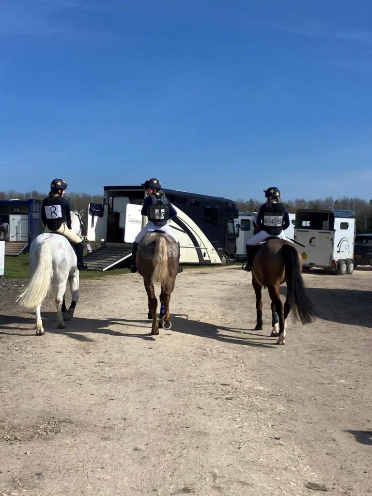 Three girls riding horses, back to the camera