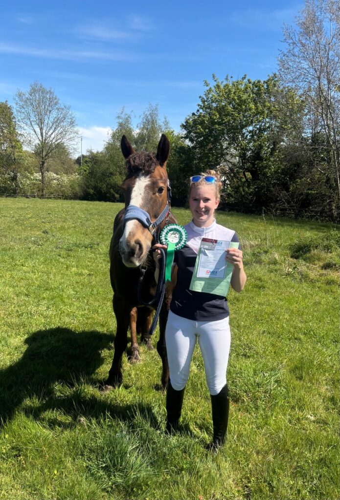 Student stood next to horse displaying her rossette 